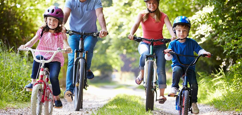 Happy family riding bikes through the forest