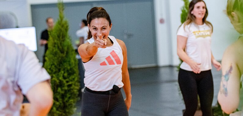 A woman does a workout and points into the camera with motivation